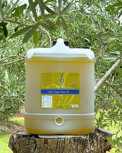 20L Olive Blue extra virgin olive oil container outdoors on tree stump, olive trees in background